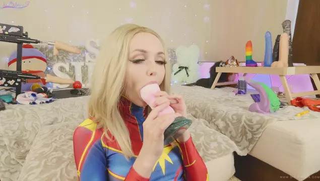 A beautiful blonde in a suit, Captain Marvel fucks herself with toys.